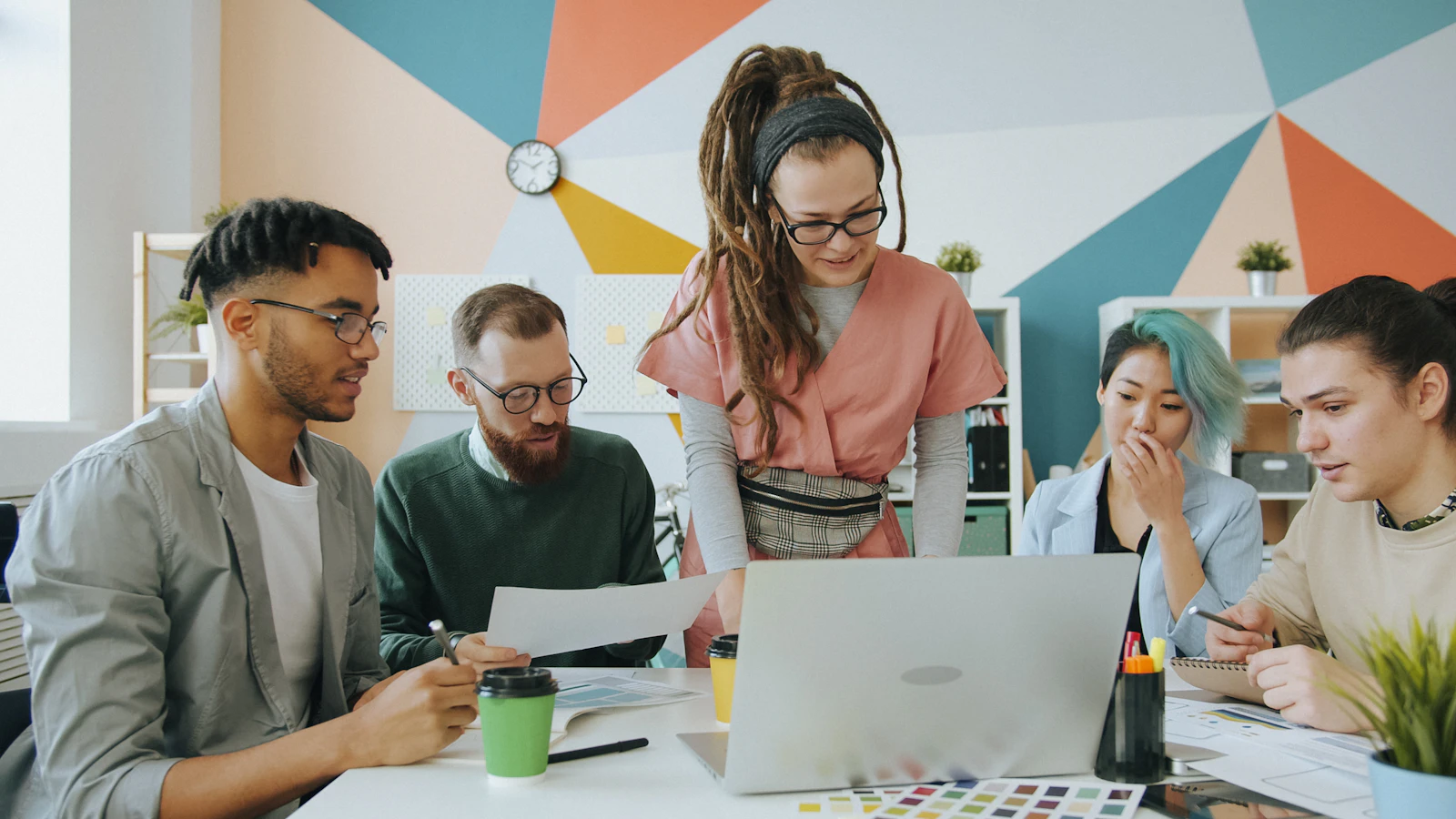 A team collaborating around a laptop in a colourful office